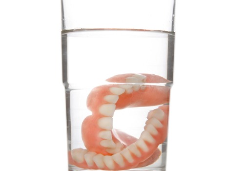 Dentures are seen soaking in a glass. Associates In Dentistry offers dentures in Peoria IL.