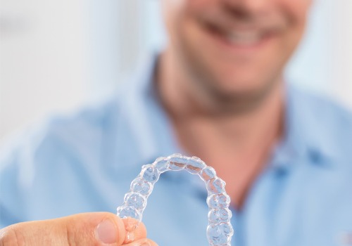 An Invisalign tray is seen in a man's hands. Associates In Dentistry offers Invisalign in Washington IL.