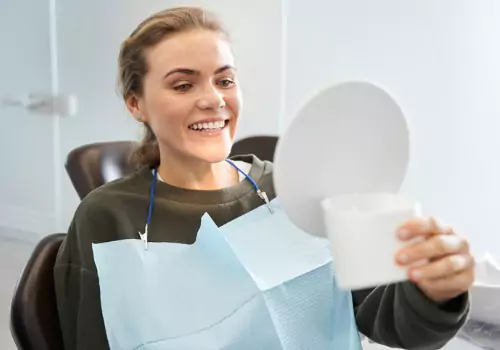 A woman in a dental chair is seen receiving examining her smile. Associates In Dentistry performs Restorative Dentistry in Elmwood IL.
