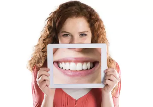 A woman poses with an image of a perfect smile. Associates In Dentistry is a Family Dentist in Canton IL