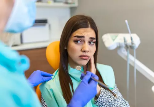 A woman is seen looking apprehensive at the dentist. Associates In Dentistry performs Root Canals.