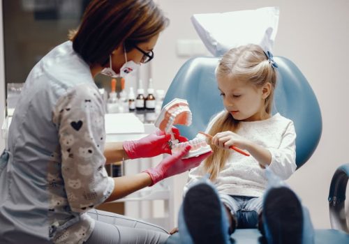 Pediatric dentist with child patient and parent at Associates in Dentistry, Canton, IL, in a friendly, kid-focused dental office.