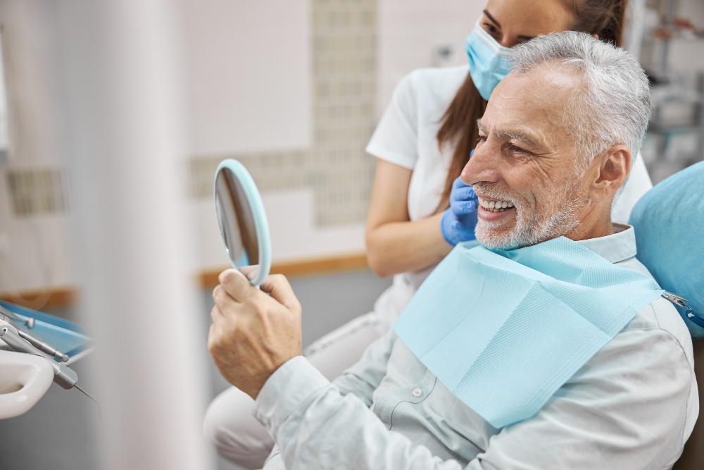 Happy dental patient in Canton, IL, smiling while viewing results of cosmetic dentistry in mirror after treatment.